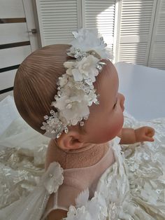 This exquisite floral ivory headband is the perfect accessory for your little one. Featuring flowers, beads and rhinestones, this headband will add a touch of glamor to any ivory baby outfit. Handcrafted with love and attention to detail, this headband is not only stylish but also comfortable to wear. A must-have for any special occasion or photo shoot, this headband is sure to make your baby stand out and make your look even more special. Attention: Free headband delivery only if purchased in c Elegant Cream Hair Accessories For Baptism, Adjustable White Bridal Headband, White Floral Hair Accessories With Matching Headband, White Adjustable Bridal Headband, Adjustable White Hair Accessories With Handmade Flowers, White Hair Accessories With Matching Headband For Baptism, Elegant White Headband For First Communion, Toddler Pearl Headband, Adjustable White Headband For First Communion