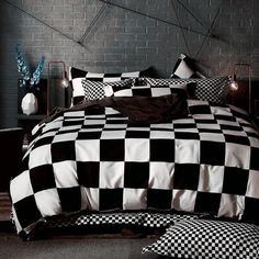 a black and white photo of a bed with checkered comforter set on it