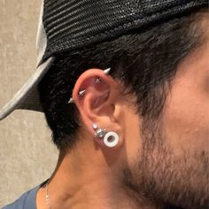 a close up of a person wearing ear piercings and a hat with no hair