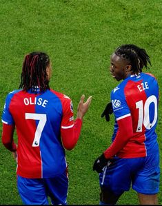 two soccer players are talking on the field