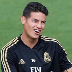 a soccer player smiles as he sits on the field