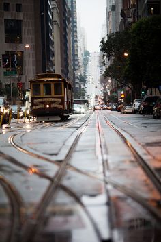 a trolley car traveling down a street next to tall buildings