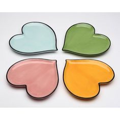 four colorful heart shaped dishes sitting on top of each other