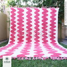 a pink and white blanket sitting in the grass