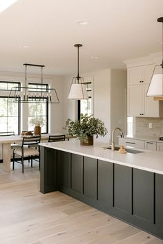 a large kitchen with an island in the middle and two pendant lights hanging from the ceiling