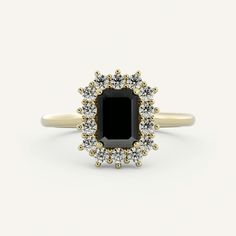 an oval black diamond surrounded by small white and yellow diamonds sits on top of a gold band