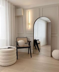 a chair and mirror in a room with white walls