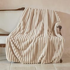 a large blanket sitting on top of a white couch next to a chair and wall