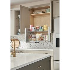 an open cabinet in the middle of a kitchen with white counter tops and gray cabinets