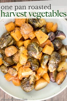 a white bowl filled with roasted veggies on top of a wooden table and text overlay reads, one pan roasted harvest vegetables