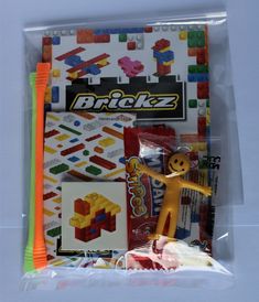 an assortment of legos in a plastic bag with markers, pencils and erasers