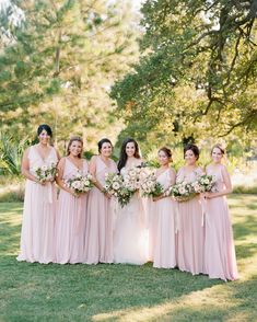 a group of bridesmaids posing for a photo in front of some bushes and trees