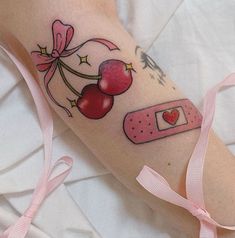 a woman's arm with tattoos on it, including cherries and a tape