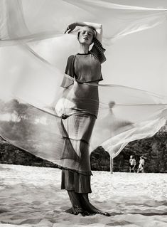 black and white photograph of woman in dress with large shawl flying around her head