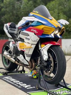 a multicolored motorcycle parked on top of a black mat