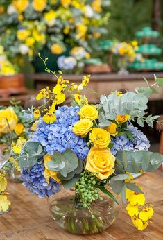 there is a vase with yellow and blue flowers in it on top of a table