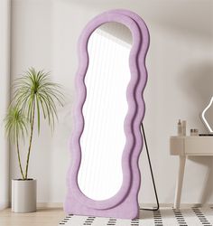 a large purple mirror sitting on top of a floor next to a potted plant