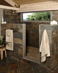 a bathroom with stone walls and flooring is shown in this image, there are towels hanging on the rack