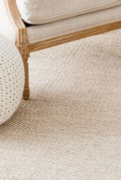 a white chair sitting on top of a rug next to a couch