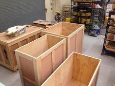 three wooden boxes sitting on top of a floor in a room filled with shelves and tools