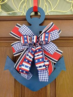 a patriotic bow hangs on the front door of a house with an anchor and checkered ribbon