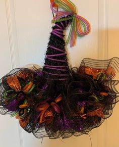 a halloween wreath made out of mesh and colorful streamers hanging on a white door