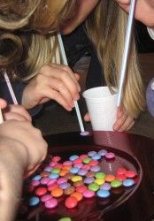 a group of people sitting at a table with drinks and candy in front of them