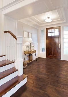 an empty entryway with wood floors and white railings, along with a wooden door