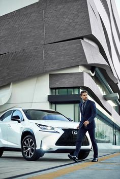 a man in a suit walking next to a white car