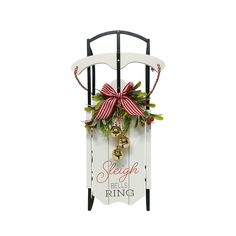 a christmas sleigh with bells and holly wreath hanging from it's side