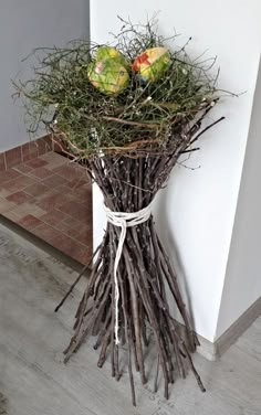 a bunch of branches with some fruit on top of it in front of a wall