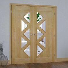 two wooden doors with mirrored glass in the center and side panels on each door, one has a potted plant behind it