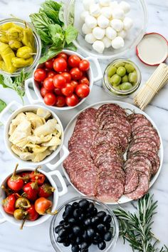 an assortment of meats, olives, tomatoes, and other foodstuffs