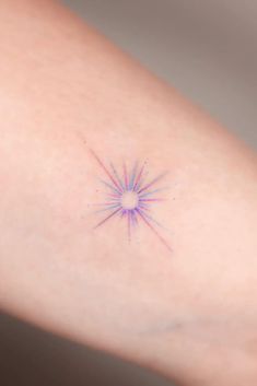 a woman's arm with a small star tattoo on it