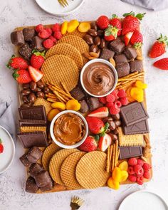 a platter with chocolate, strawberries, and crackers on it next to other desserts