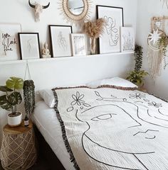 a bed with pictures on the wall above it and plants in vases next to it