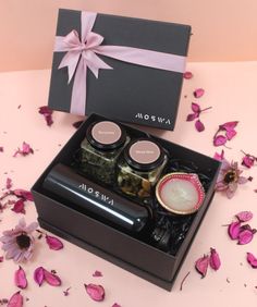 an open gift box with two jars and spoons in it on a pink surface