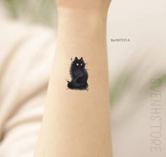 a small black cat tattoo on the wrist