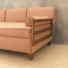 an orange and white striped couch sitting on top of a hard wood floor next to a wall