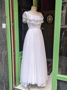 a white dress on display in front of a green door