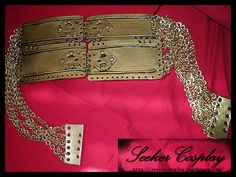 a gold purse with chains and studs on the front, sitting on a pink cloth