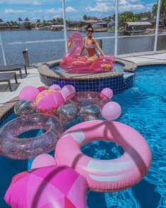 a woman sitting on an inflatable raft next to a pool filled with floats