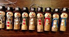 a group of snowmen made out of wine corks hanging from a string on a wooden table