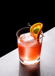 an orange cocktail garnished with an orange slice