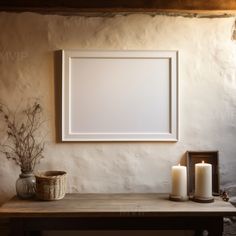 a white frame sitting on top of a wooden table next to a vase and two candles