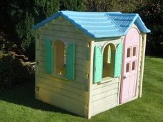 a toy house made out of plastic with windows and shutters on each side, in the grass