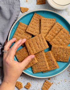 a blue plate topped with crackers next to a cup of milk