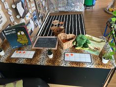 a table with books and stuffed animals on it in front of a bulletin board wall