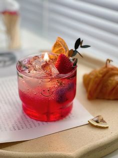 a red drink sitting on top of a wooden tray