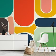 a living room with a large colorful wall mural on the wall and a white cabinet